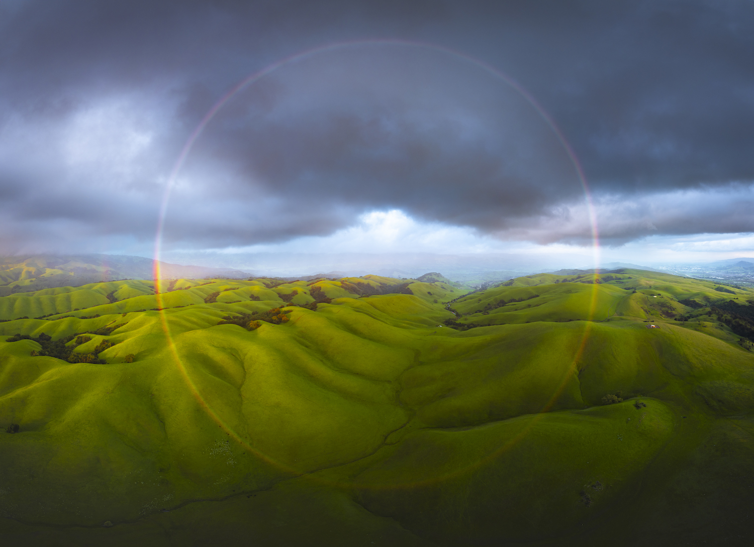 a circular rainbow over rolling green hills