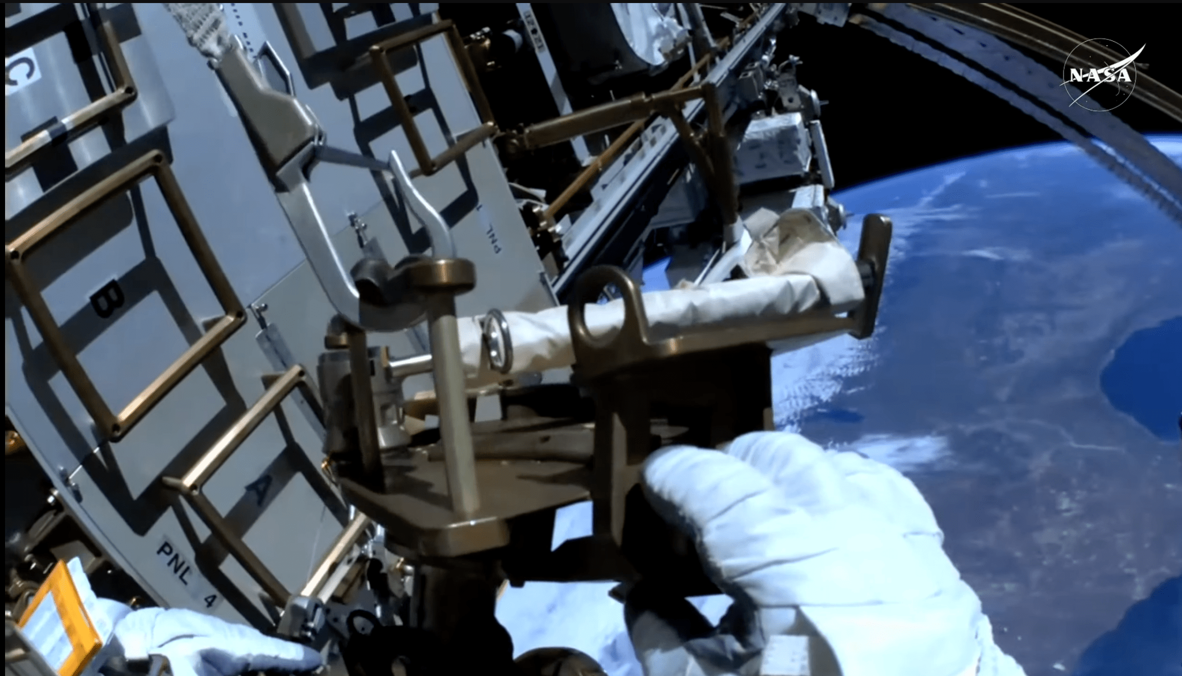 First person shot of astronaut hands repairing ISS tool during spacewalk above Earth